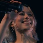 Phoebe Bridgers se apresentando ao vivo com um microfone